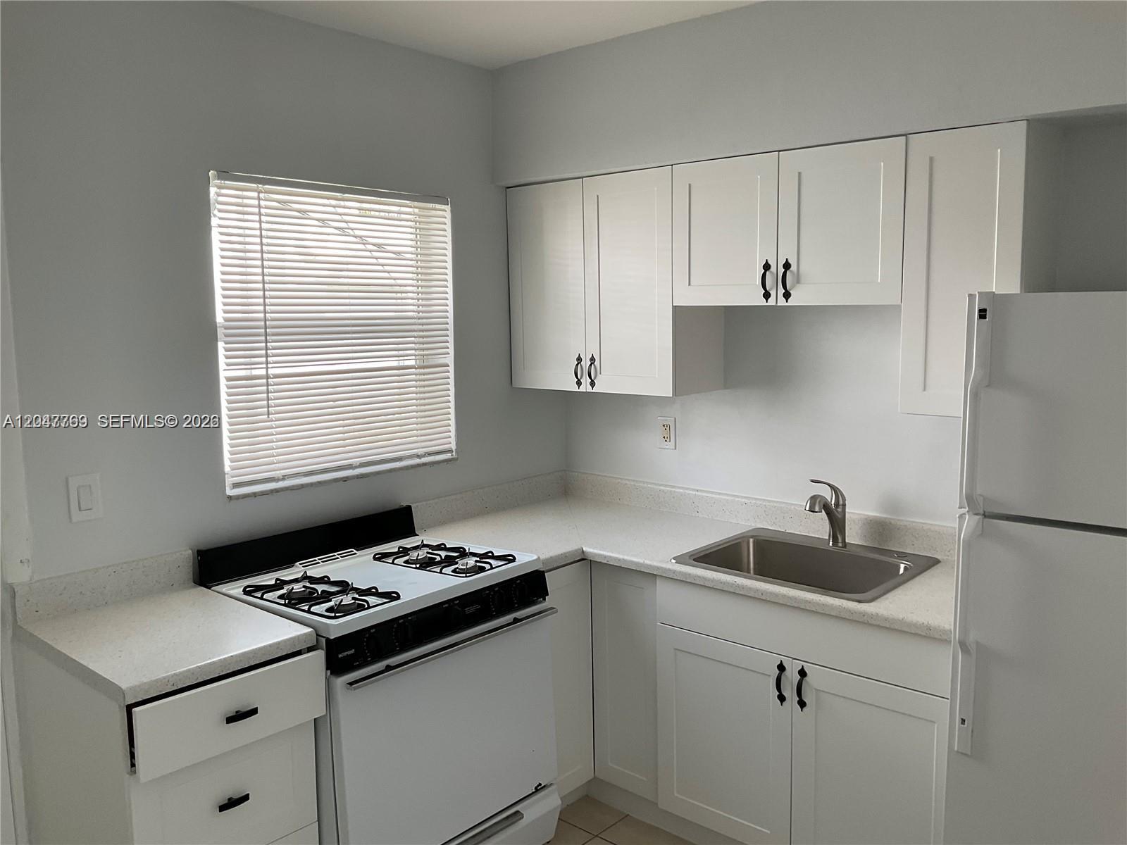 A kitchen features white cabinets, a white gas stove, a stainless steel sink, and countertops — 1420 NE 171st St # 2, North Miami Beach FL 33162, NORTH MIAMI BEACH, FL