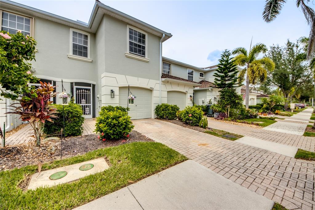 A two-story townhouse with a paved driveway, a one-car garage, and landscaped front yard — 8668 ATHENA COURT, LEHIGH ACRES, FL