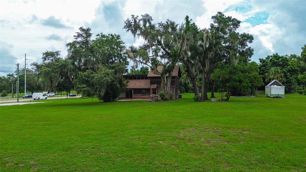 A two-story wooden house sits on a large grassy lot with mature trees — 11700 VALLEY ROAD, DADE CITY, FL
