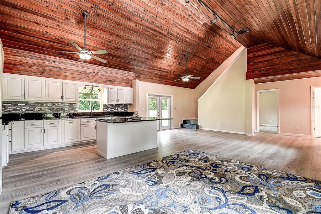A kitchen with white cabinets and a center island under a vaulted wood-paneled ceiling — 11700 VALLEY ROAD, DADE CITY, FL