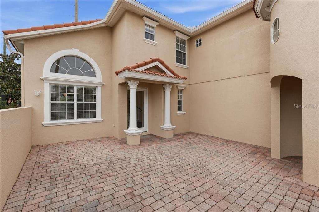 A paved patio sits in front of a tan two-story house with white columns — 11854 VIA LUCERNA CIRCLE, WINDERMERE, FL