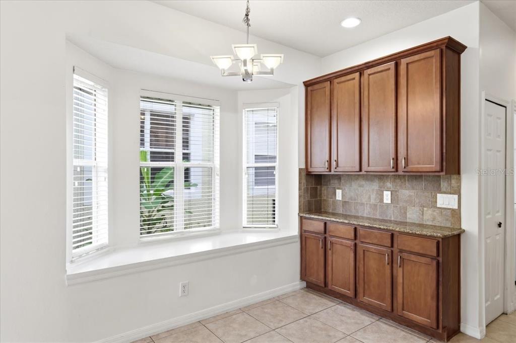 A dining area features a bay window with a bench seat and wood cabinetry with countertops — 11854 VIA LUCERNA CIRCLE, WINDERMERE, FL