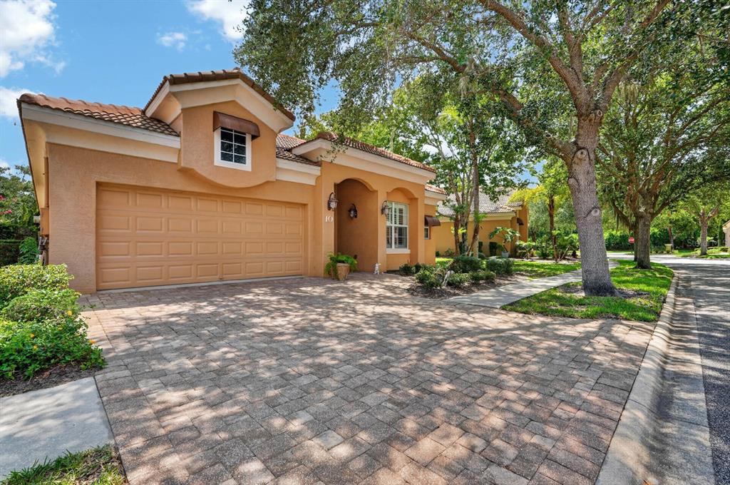A tan stucco house with a tiled roof and a paved driveway sits under large trees — 10 LAKESIDE WAY, PALM COAST, FL