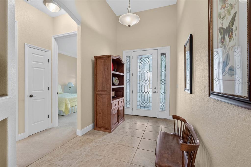 A tiled entryway features a wooden hutch, a bench, and a glass-paneled front door — 10 LAKESIDE WAY, PALM COAST, FL