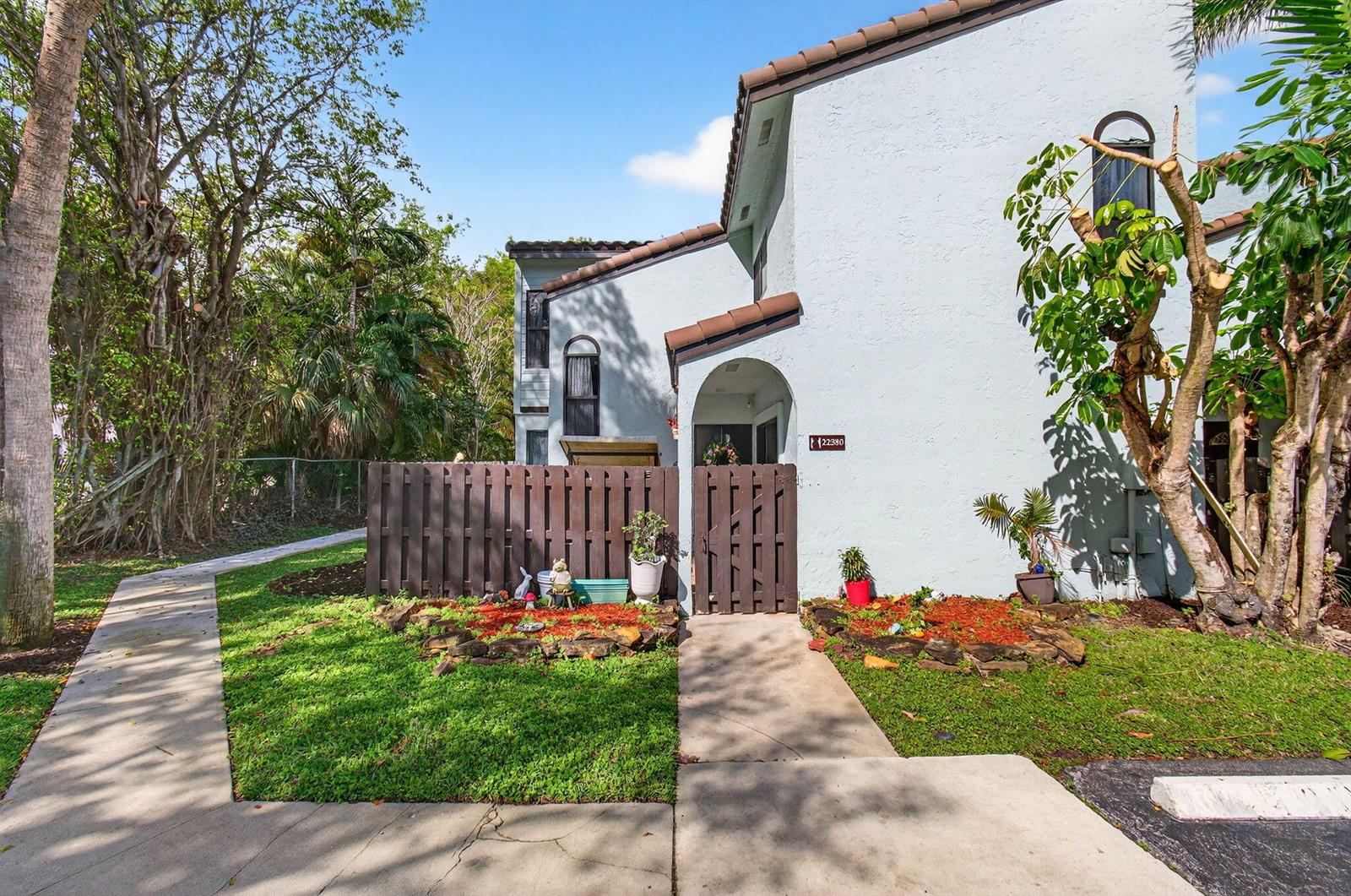 A light blue two-story townhouse features a brown wooden fence and a small front garden — 22380 Pineapple Walk Drive, Boca Raton FL 33433, BOCA RATON, FL