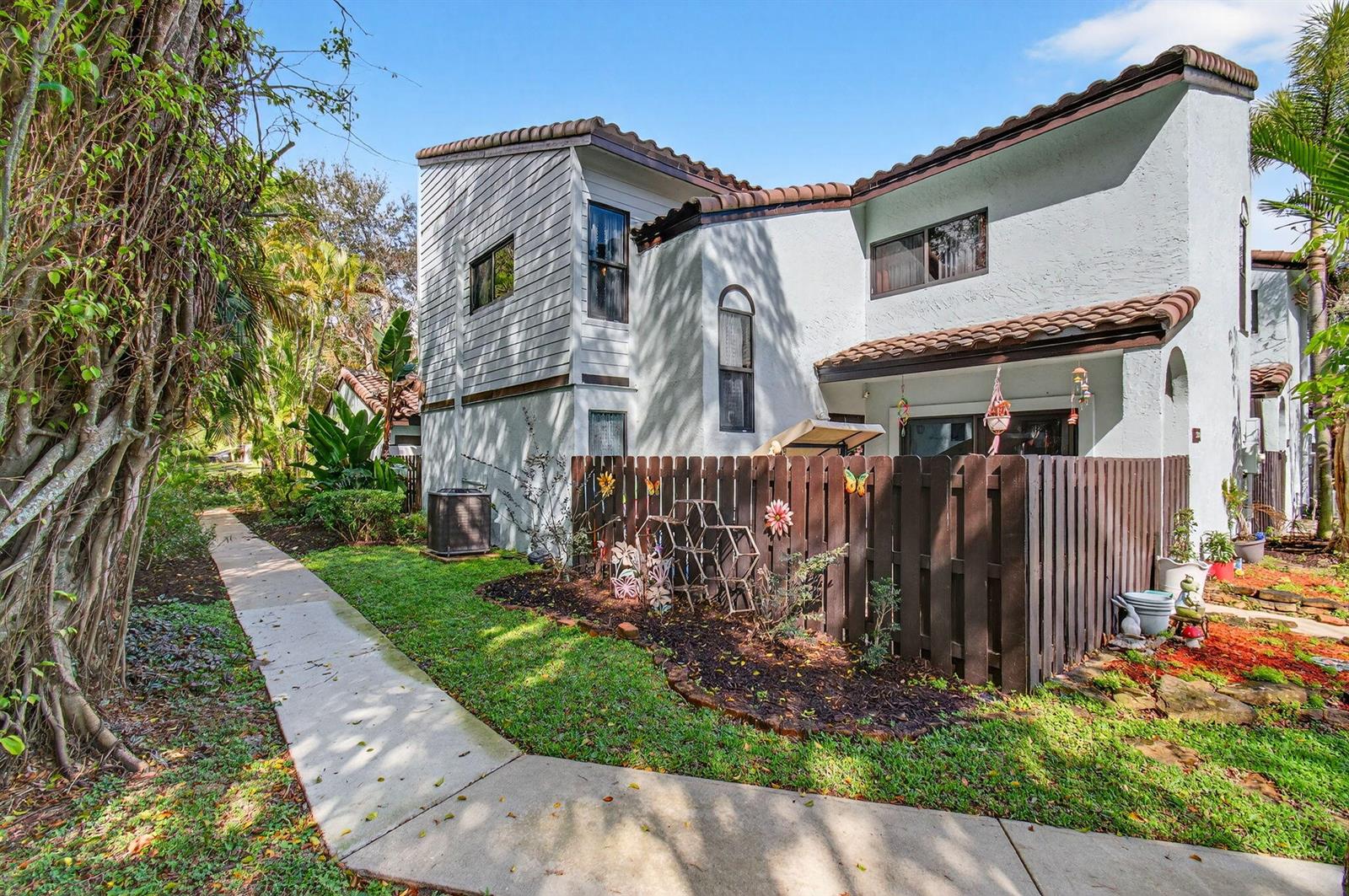 Exterior view of a two-story townhouse with a fenced patio and a concrete walkway — 22380 Pineapple Walk Drive, Boca Raton FL 33433, BOCA RATON, FL