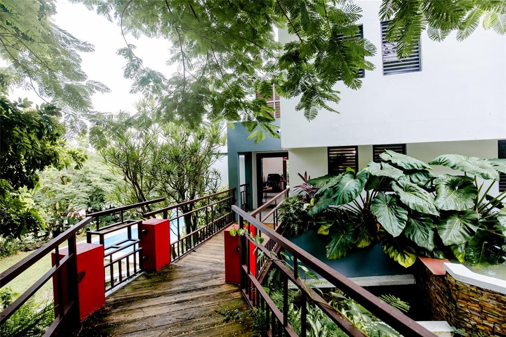A wooden walkway with red railings leads to the entrance of a modern white house — PR 992 KM3.4 3 ST VILLAS DE LUQUILLO UNIT D18, LUQUILLO, PR