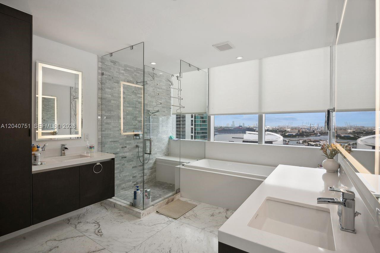 A modern bathroom features a glass-enclosed shower, a soaking tub, and double vanities — 851 NE 1st Ave # 1711, Miami FL 33132, MIAMI, FL