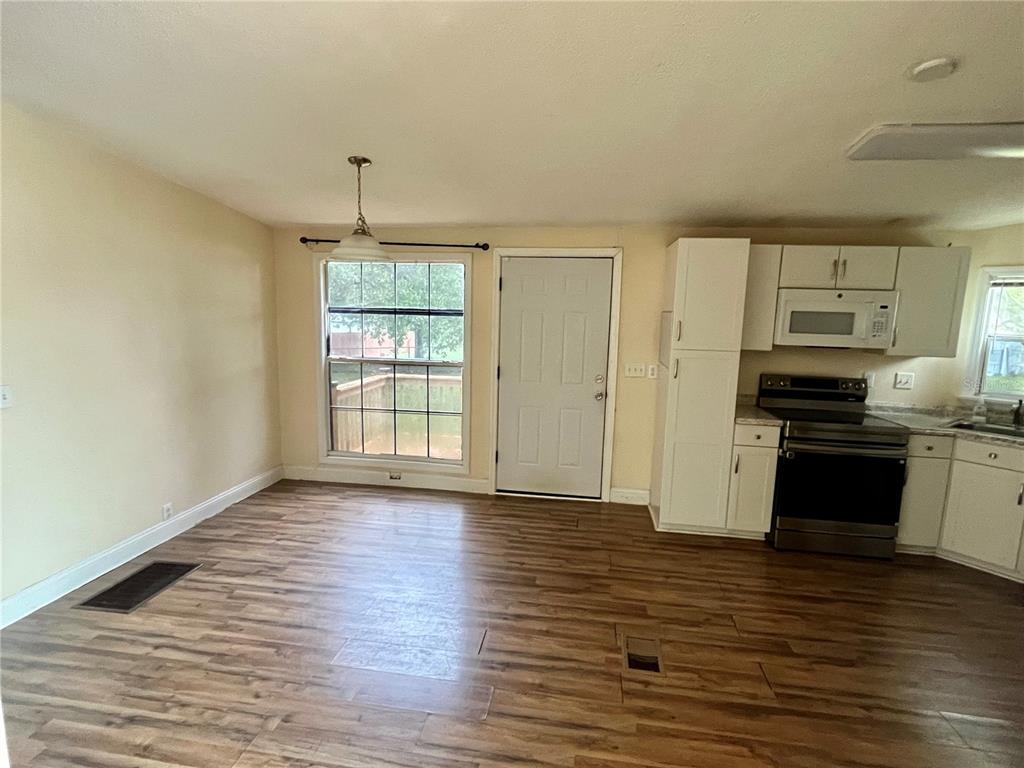 A kitchen and dining area with wood-look flooring, white cabinets, and a back door — 14152 SE 59TH AVENUE, SUMMERFIELD, FL