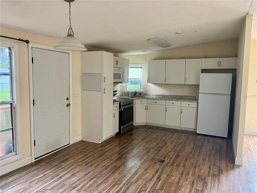 A kitchen with white cabinets, stainless steel appliances, and wood-look flooring — 14152 SE 59TH AVENUE, SUMMERFIELD, FL