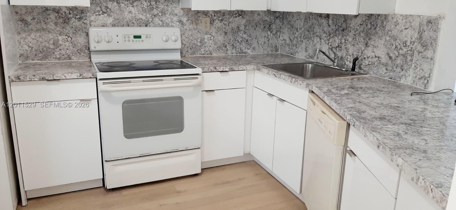 A kitchen features white cabinets, gray marble-patterned countertops, and a white electric range — 1750 NE 191st St # 2, Miami FL 33179, MIAMI, FL