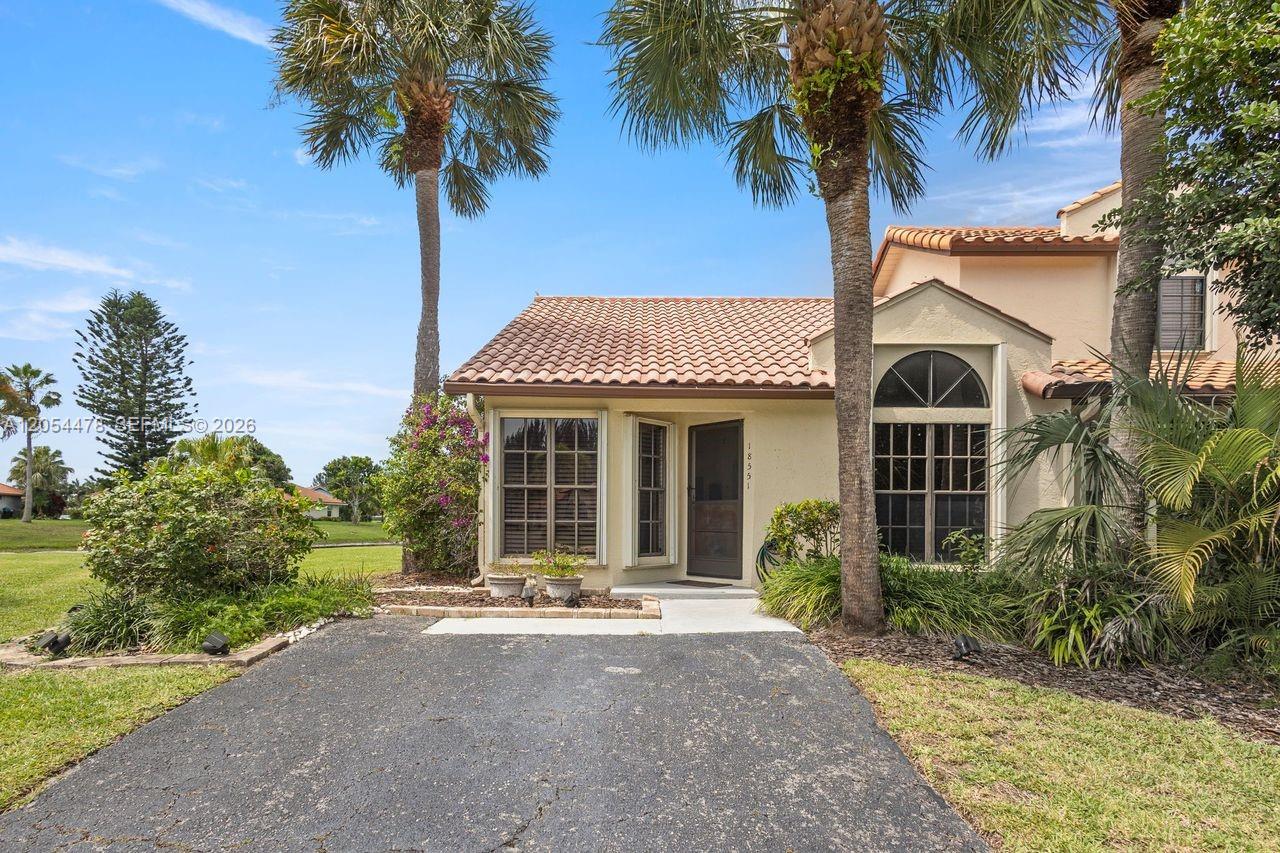 A single-story house with a tiled roof, a paved driveway, and palm trees in front — 18551 Woodstream Dr, Boca Raton FL 33498, BOCA RATON, FL