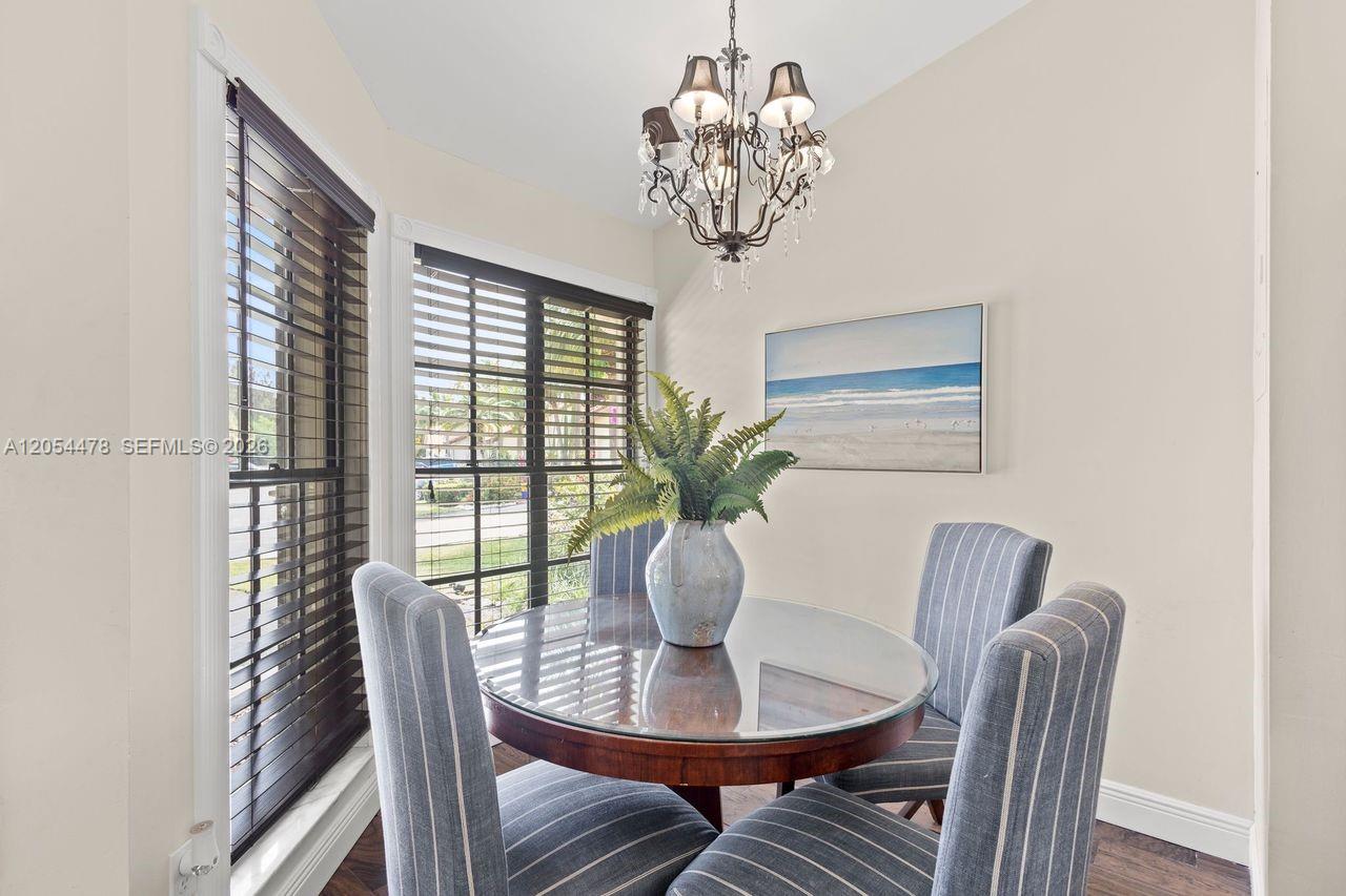 A dining area features a glass-topped table, striped chairs, a chandelier, and large windows — 18551 Woodstream Dr, Boca Raton FL 33498, BOCA RATON, FL
