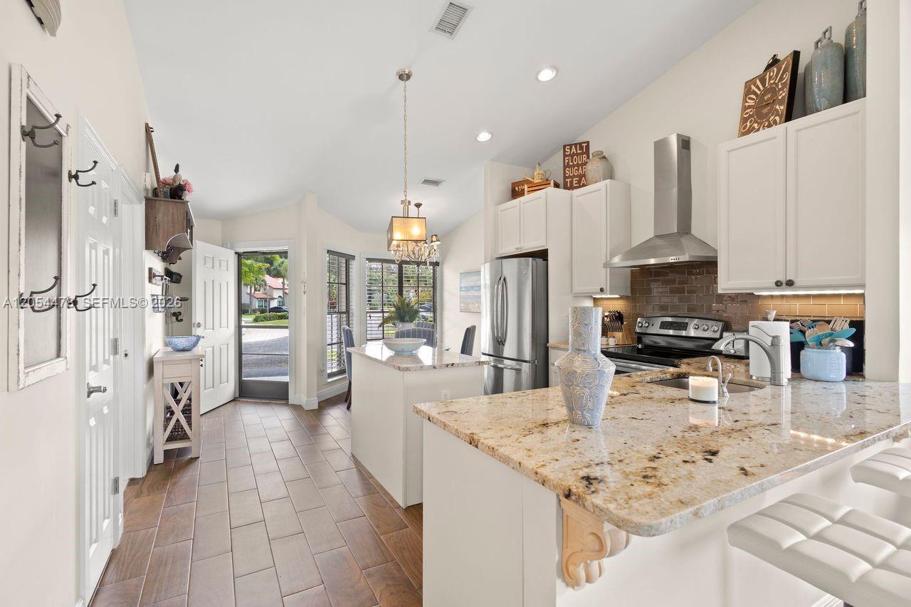 A kitchen features granite countertops, white cabinetry, stainless steel appliances, and tile flooring — 18551 Woodstream Dr, Boca Raton FL 33498, BOCA RATON, FL