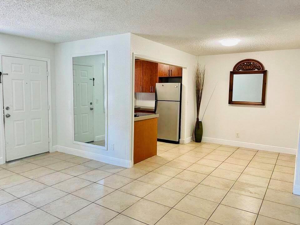 A tiled room features a white front door, a large wall mirror, and an open kitchen — 400 NW 65th Avenue # 114, Margate FL 33063, MARGATE, FL