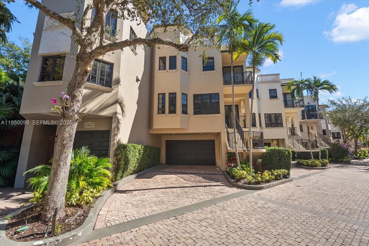 A multi-story townhouse with a paved driveway, garage, and palm trees under a blue sky — 3471 Main Hwy # 1240, Miami FL 33133, MIAMI, FL