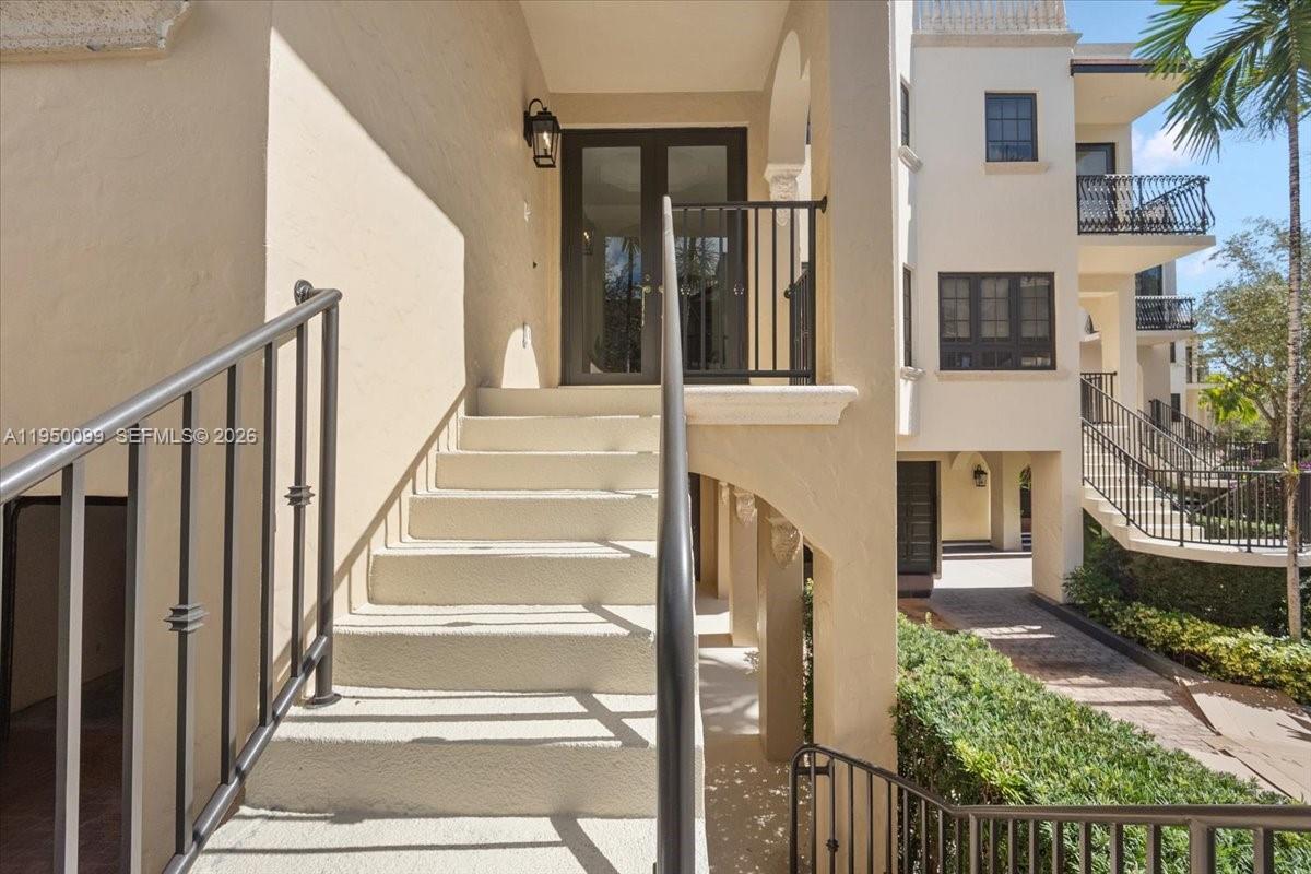An outdoor staircase with black metal railings leads to a covered entryway with double doors — 3471 Main Hwy # 1240, Miami FL 33133, MIAMI, FL