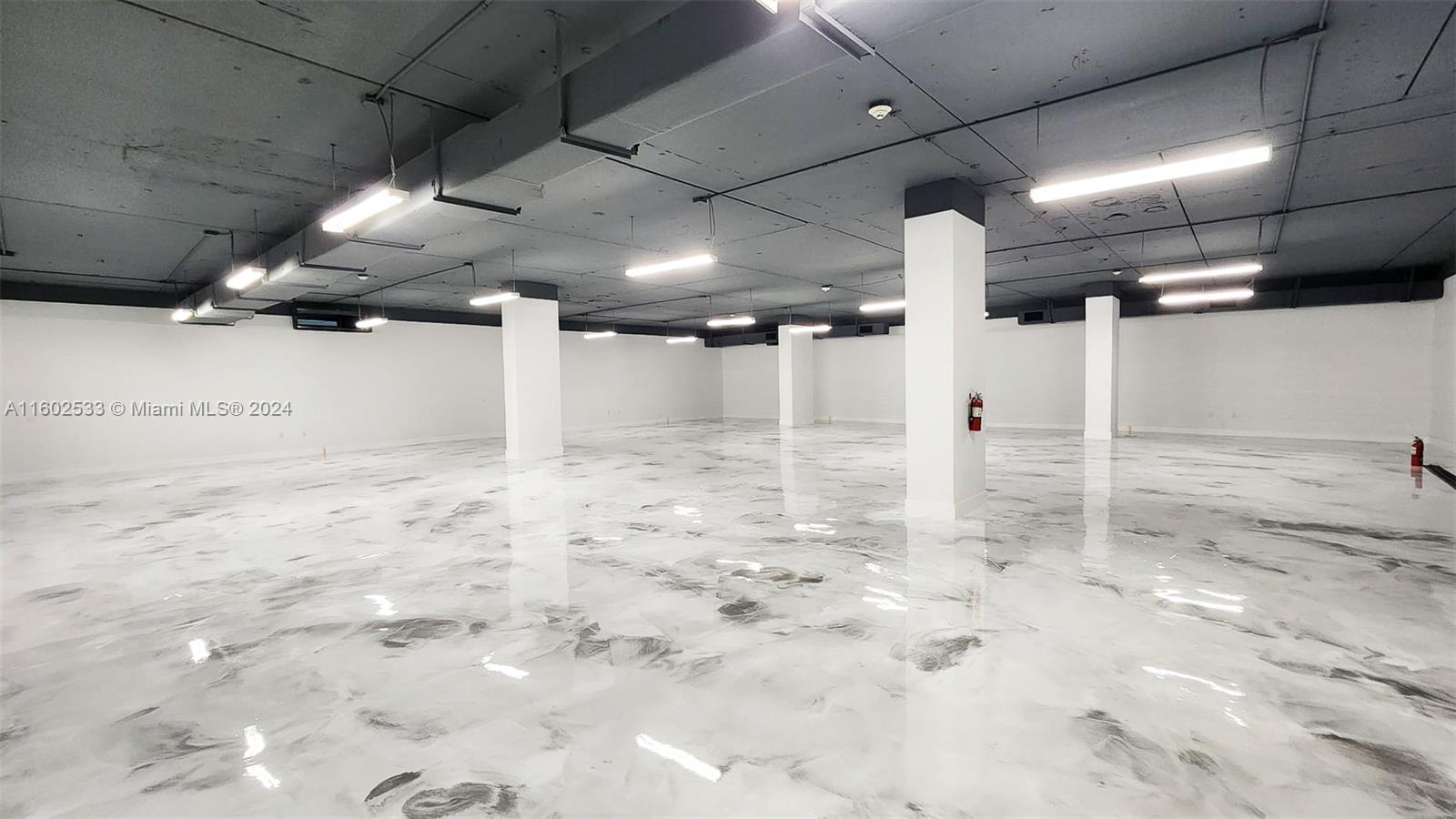 An empty commercial space features a glossy marbled floor, white walls, and exposed ceiling beams — 42 NW 27th Ave # 305, Miami FL 33125, MIAMI, FL