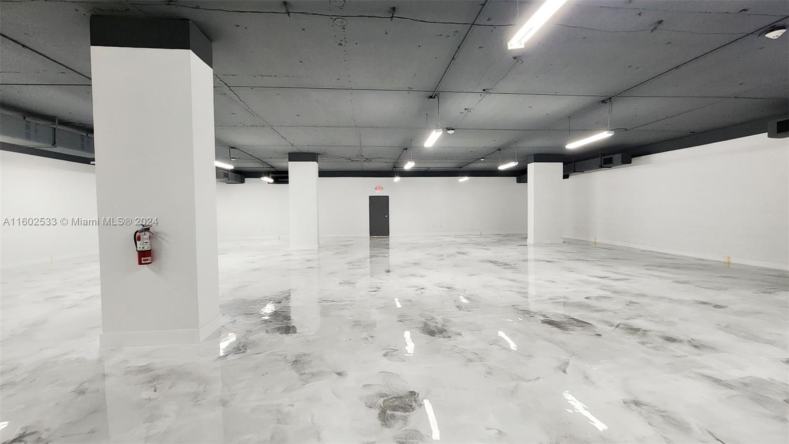 An empty commercial space features a gray concrete ceiling, white support columns, and a marbled floor — 42 NW 27th Ave # 305, Miami FL 33125, MIAMI, FL