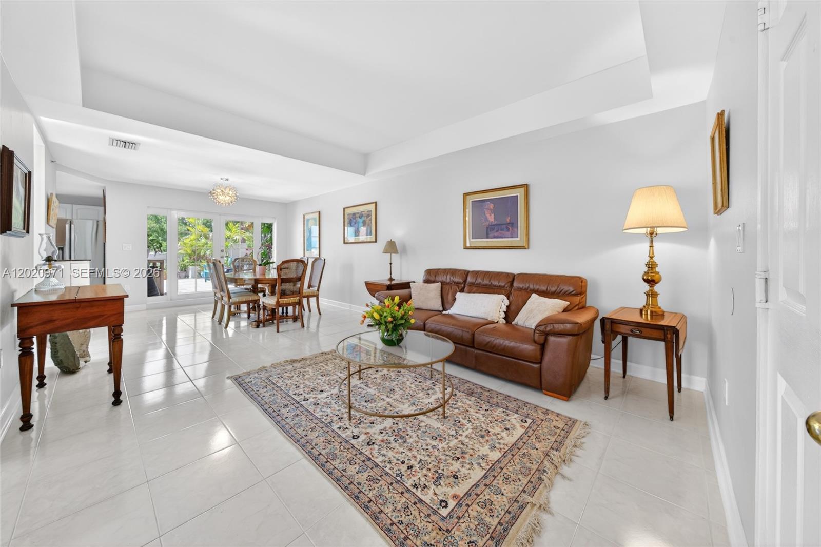 A living and dining area features white tile floors, a brown leather sofa, and glass doors — 323 Navarre Ave # 403, Coral Gables FL 33134, CORAL GABLES, FL