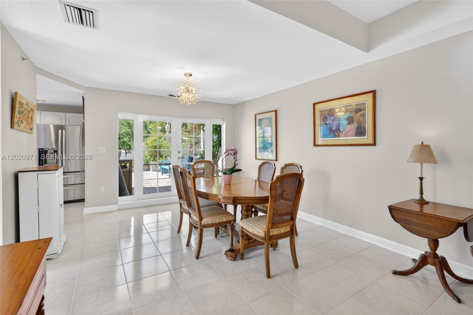 A dining room features a wooden table with cane-back chairs, tile flooring, and glass doors — 323 Navarre Ave # 403, Coral Gables FL 33134, CORAL GABLES, FL