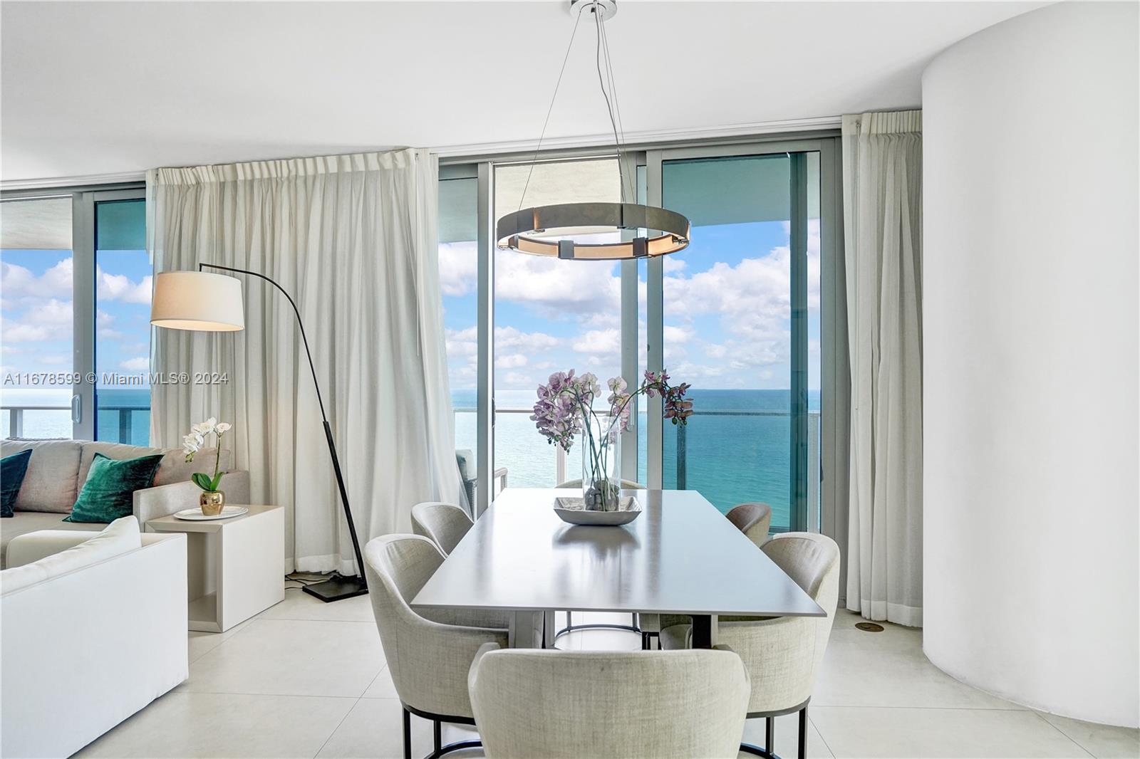 A dining area features a modern table, upholstered chairs, and floor-to-ceiling windows overlooking the ocean — 4111 S Ocean Dr # 1201, Hollywood FL 33019, HOLLYWOOD, FL