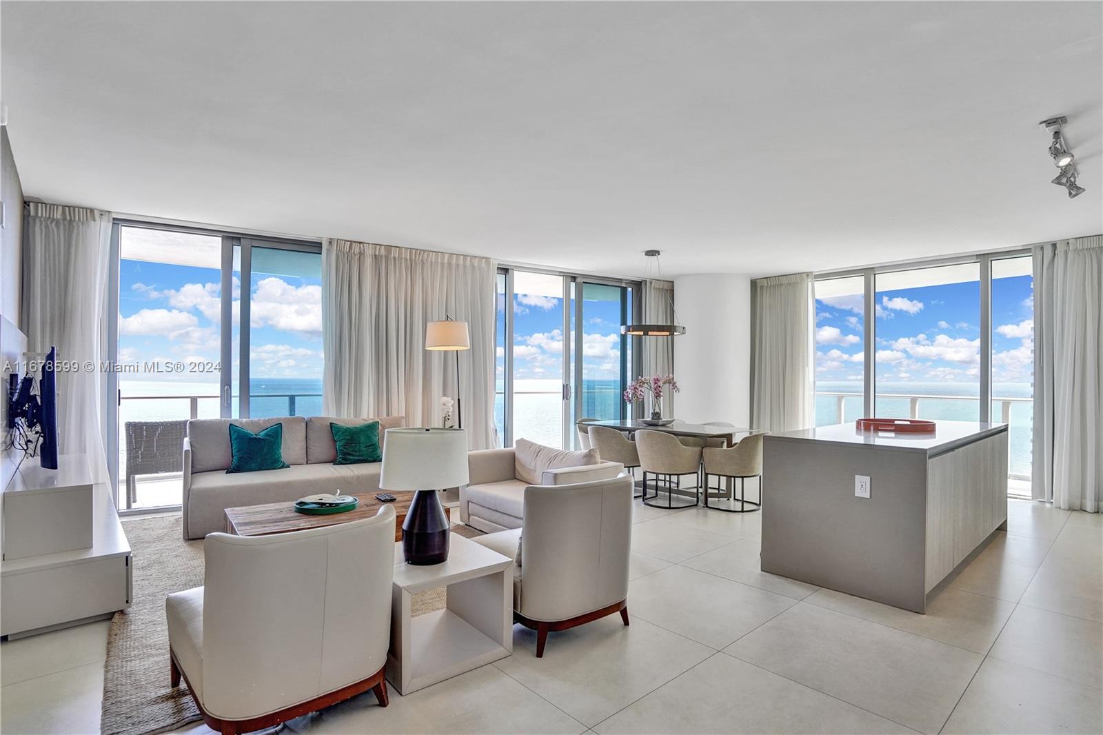 A modern living and dining area features floor-to-ceiling windows with ocean views and tile flooring — 4111 S Ocean Dr # 1201, Hollywood FL 33019, HOLLYWOOD, FL
