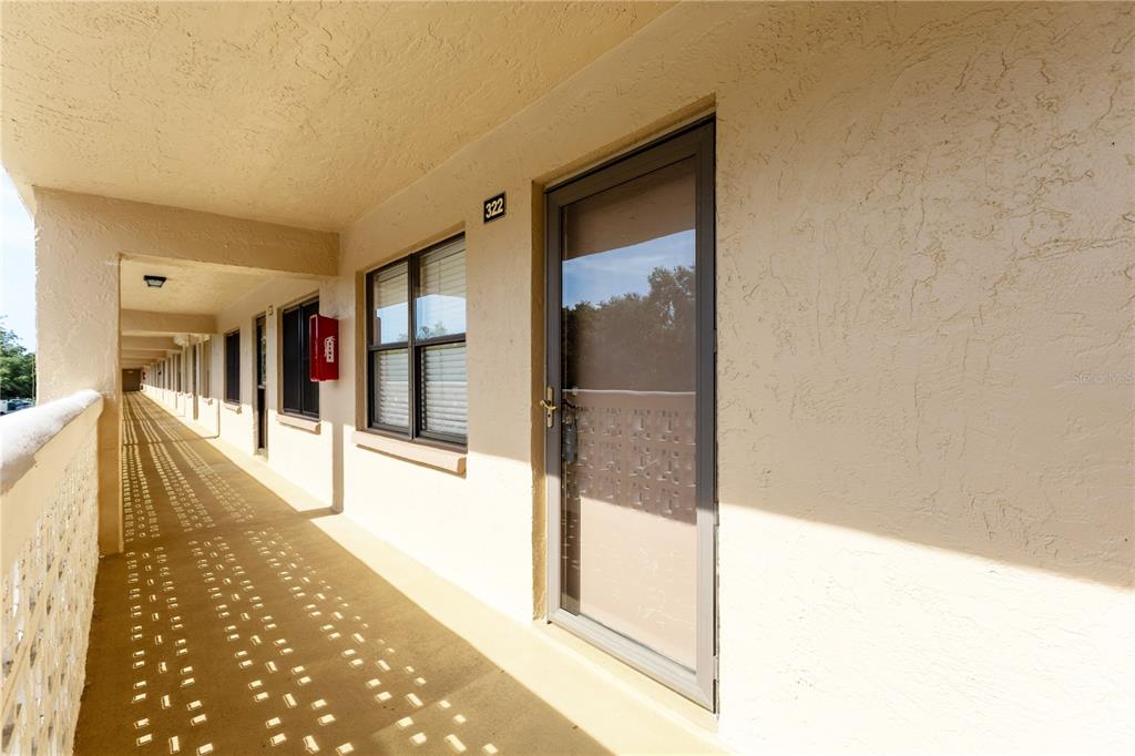 An exterior walkway leads to a unit door marked 322 in a multi-story apartment building — 5080 LOCUST STREET NE UNIT 322, ST PETERSBURG, FL