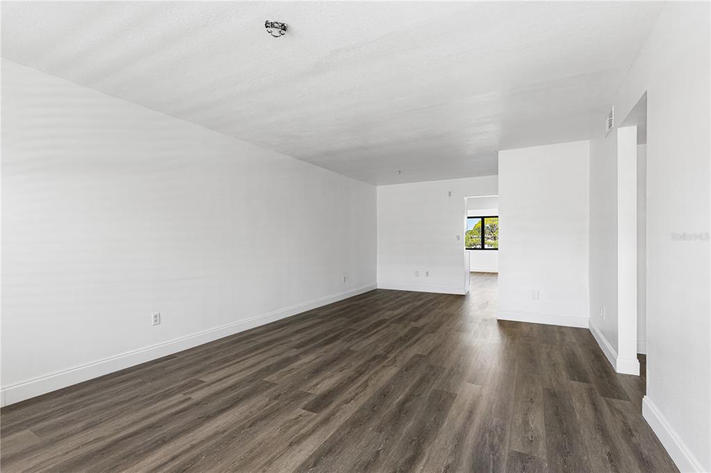 An empty room with white walls, wood-look flooring, and a doorway leading to another area — 5080 LOCUST STREET NE UNIT 322, ST PETERSBURG, FL
