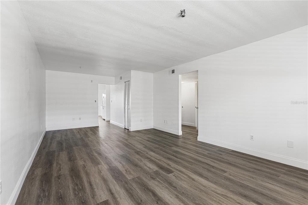 An empty room with white walls and dark wood-look flooring features two doorways — 5080 LOCUST STREET NE UNIT 322, ST PETERSBURG, FL