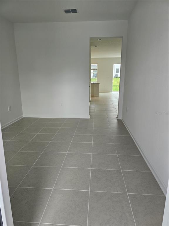 A room with light gray tile flooring leads through a doorway into an open living area — 6045 ZEN WAY UNIT 6045, CLERMONT, FL