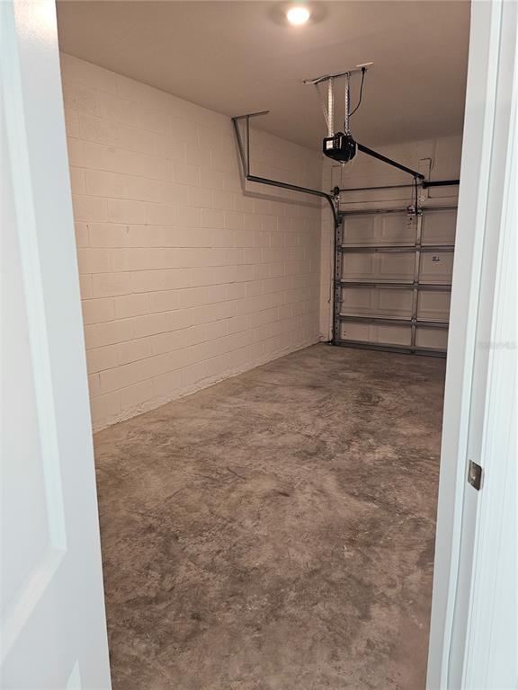An empty garage with a concrete floor, white painted block walls, and a sectional door — 6045 ZEN WAY UNIT 6045, CLERMONT, FL