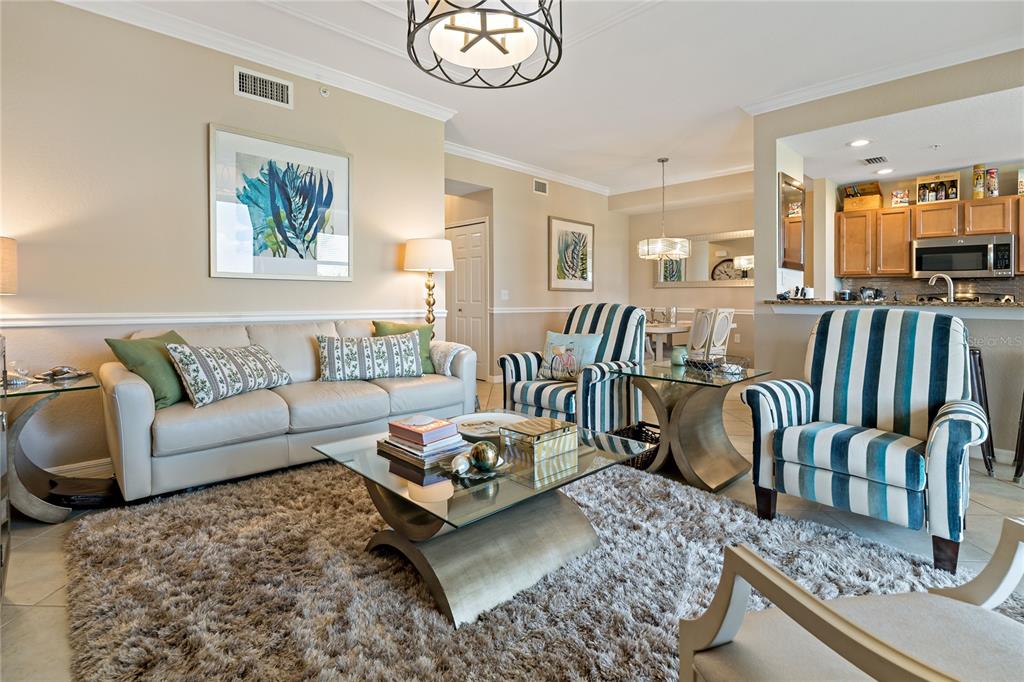 A living room features a beige sofa, two striped armchairs, and a glass coffee table — 7015 RIVER HAMMOCK DRIVE UNIT 306, BRADENTON, FL