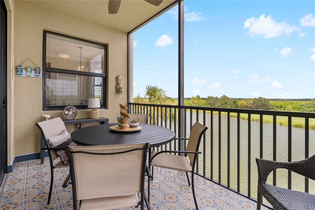A screened-in balcony features patterned tile flooring, a dining set, and a view of water — 7015 RIVER HAMMOCK DRIVE UNIT 306, BRADENTON, FL