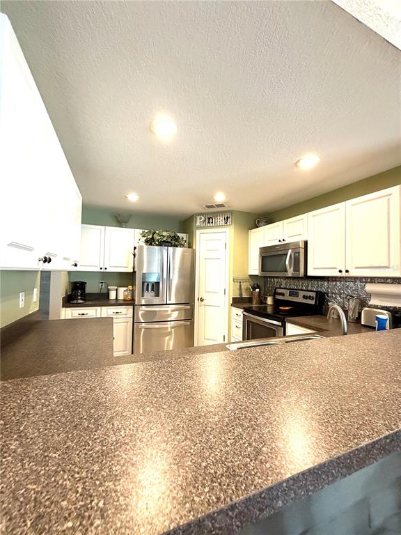 A kitchen features white cabinets, dark countertops, stainless steel appliances, and recessed lighting — 902 E TOMLIN STREET, PLANT CITY, FL