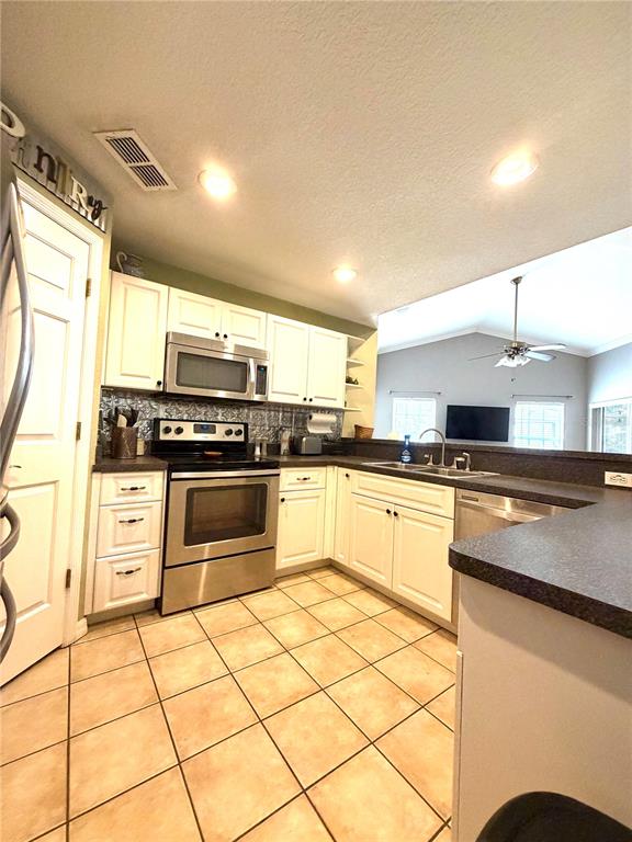 A kitchen features white cabinets, stainless steel appliances, dark countertops, and light tile flooring — 902 E TOMLIN STREET, PLANT CITY, FL