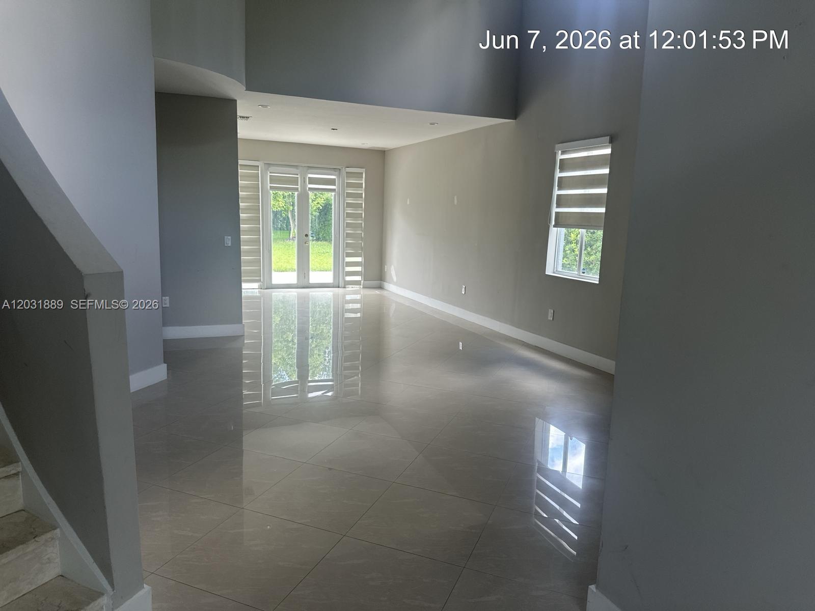 An empty room with light-colored tile flooring, gray walls, and glass double doors — 1974 SE 23rd Ct, Homestead FL 33035, HOMESTEAD, FL