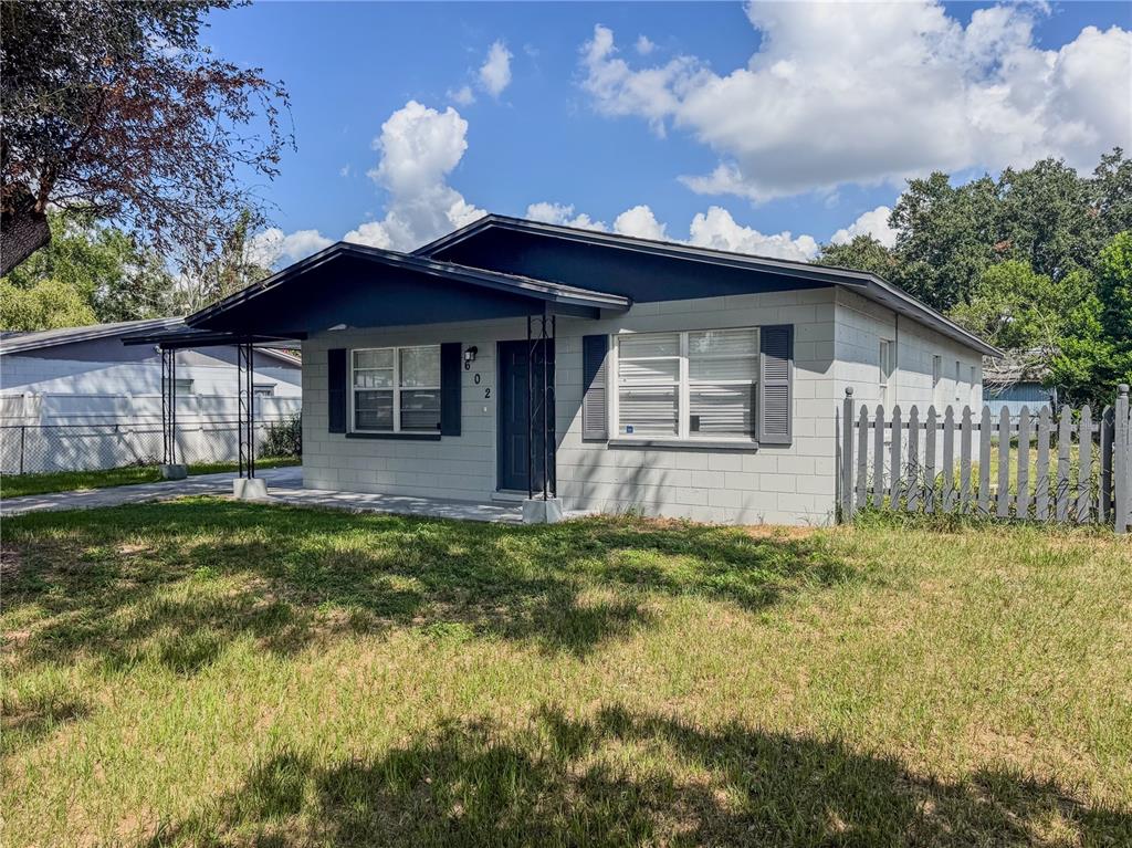 A single-story house with a gray concrete block exterior, dark trim, and a front porch — 602 TAYLOR BOULEVARD, WINTER HAVEN, FL