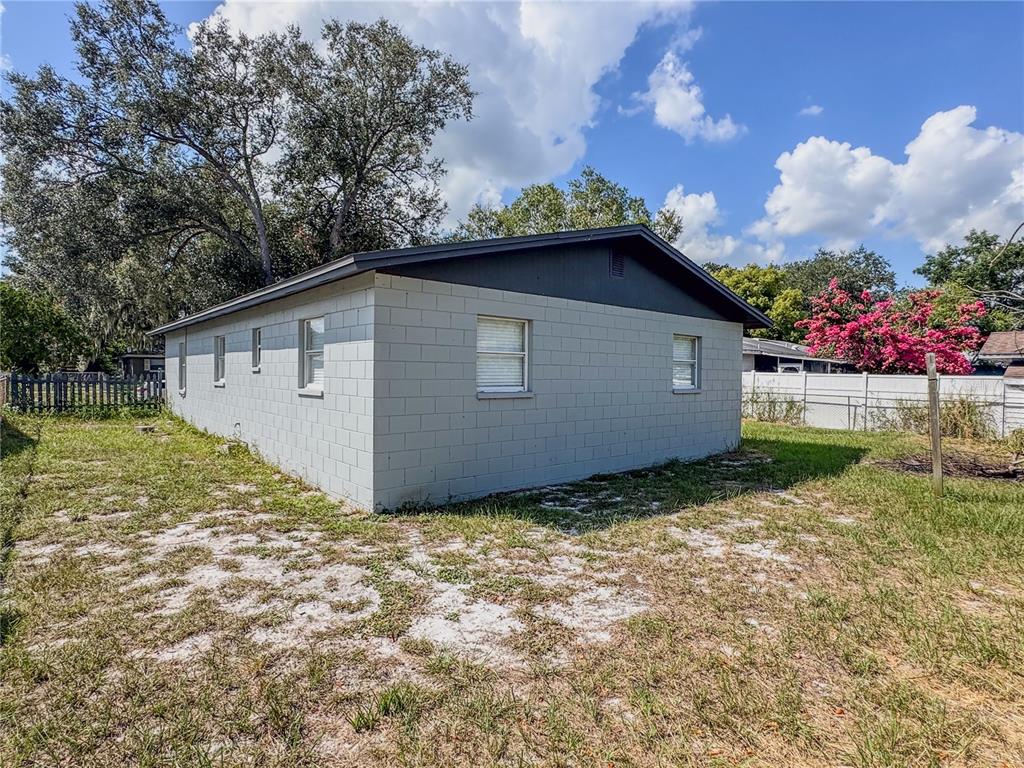 A gray concrete block house exterior with a dark roof and a grassy backyard — 602 TAYLOR BOULEVARD, WINTER HAVEN, FL