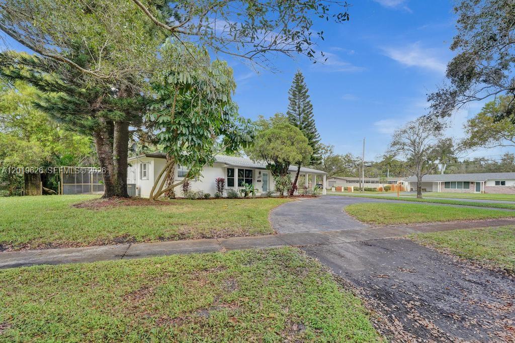 A single-story white house with a curved driveway and mature trees in the front yard — 101 SW 53rd Ave, Plantation FL 33317, PLANTATION, FL