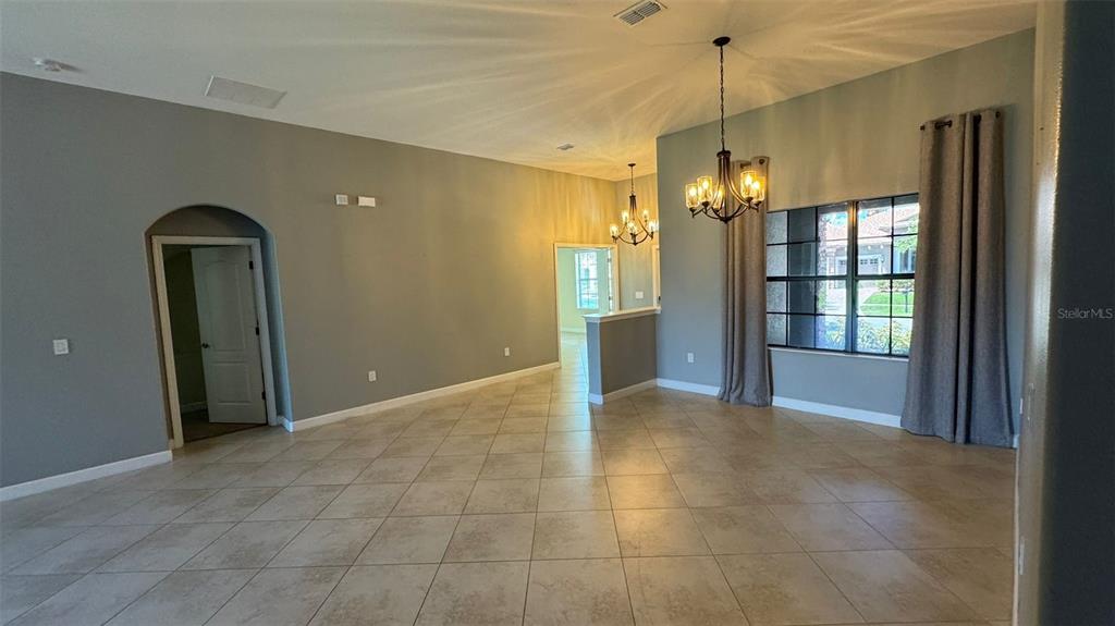 A spacious room with tile flooring, two chandeliers, and large windows with gray curtains — 1428 DEUCE CIRCLE, DAVENPORT, FL