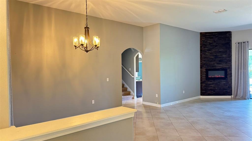A dining area features a chandelier, a tiled floor, and a stone-accented fireplace wall — 1428 DEUCE CIRCLE, DAVENPORT, FL