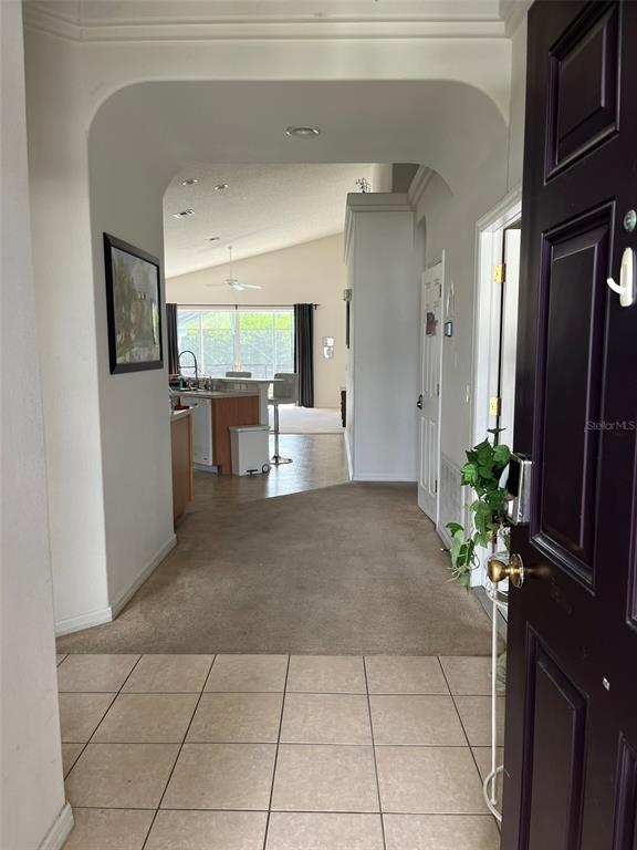 A view from an entryway looking into a kitchen and living area with tile flooring — 16628 FRESH MEADOW DRIVE, CLERMONT, FL