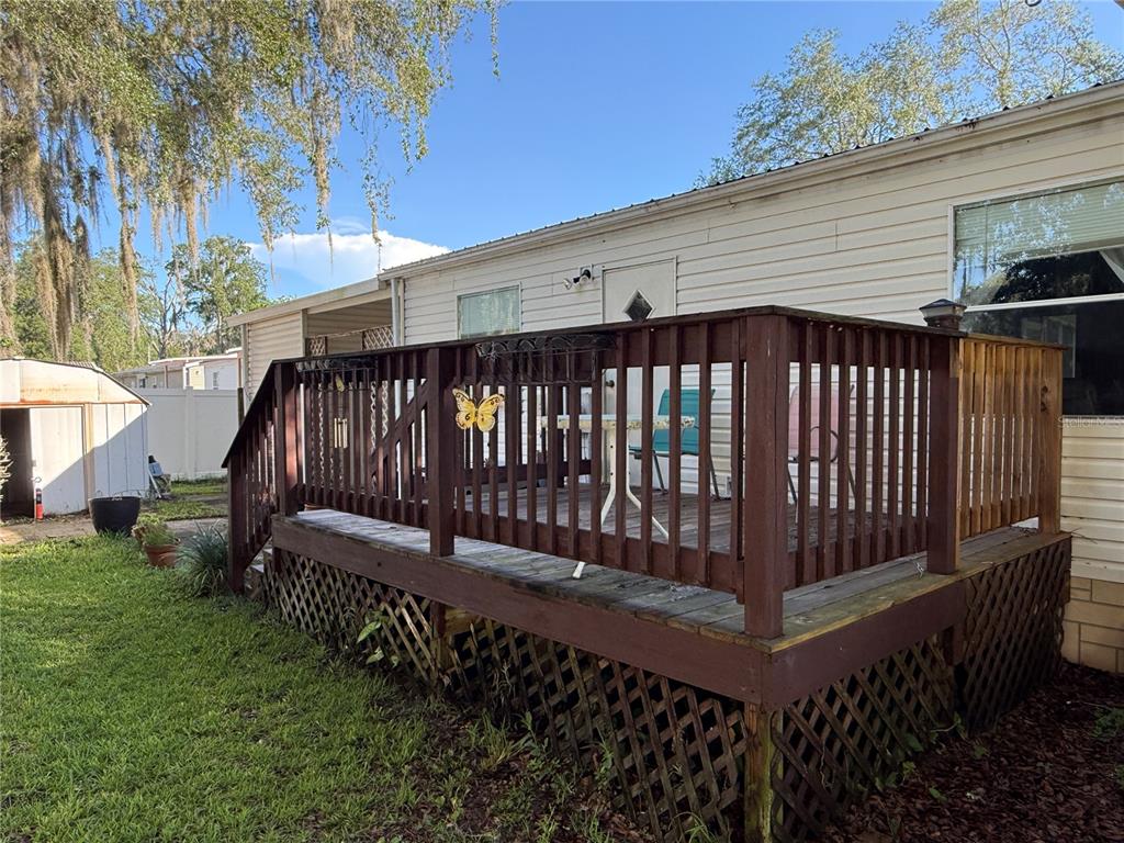 A wooden deck with railings and lattice skirting is attached to the side of a house — 8634 TREASURE ISLAND ROAD, LEESBURG, FL