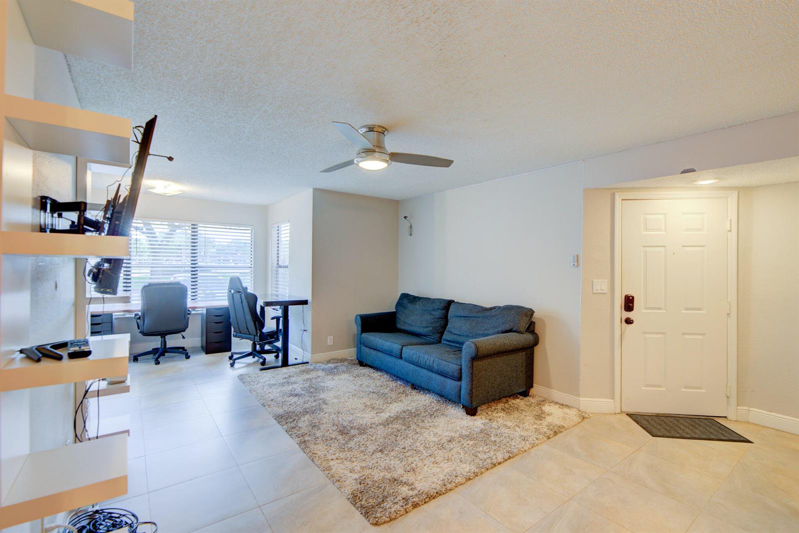 A living room features a blue sofa on a rug, a desk area, and tile flooring — 2900 S University Drive # 9104, Davie FL 33328, DAVIE, FL