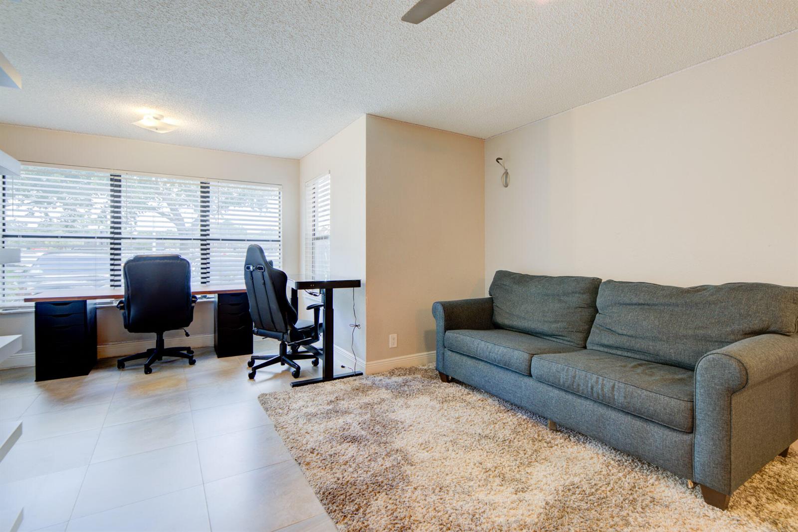 A home office features a long desk with two chairs, a gray sofa, and tile flooring — 2900 S University Drive # 9104, Davie FL 33328, DAVIE, FL