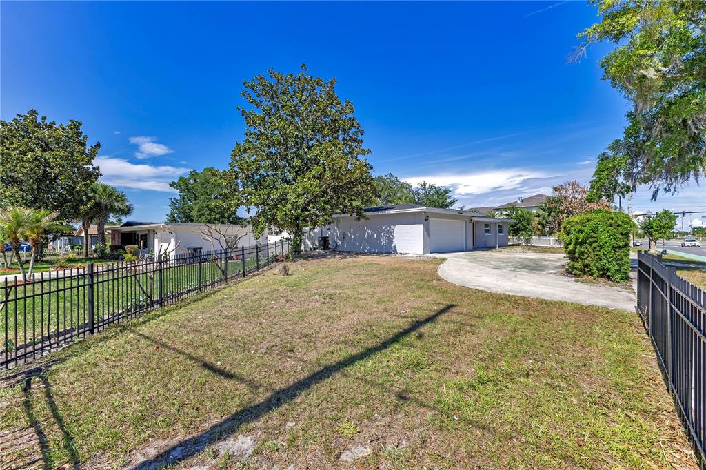 A single-story gray house with a white garage door and a paved driveway behind a fence — 2419 ORANGE CENTER BOULEVARD, ORLANDO, FL