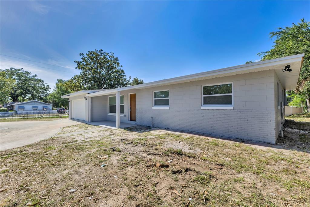 A single-story house with a gray brick exterior, a wooden front door, and a gated driveway — 2419 ORANGE CENTER BOULEVARD, ORLANDO, FL