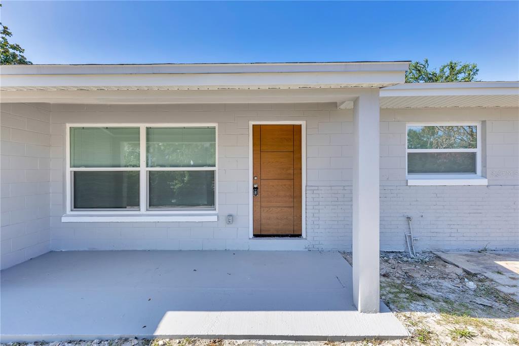 A gray house with a paved driveway and a black metal fence under a blue sky — 2419 ORANGE CENTER BOULEVARD, ORLANDO, FL