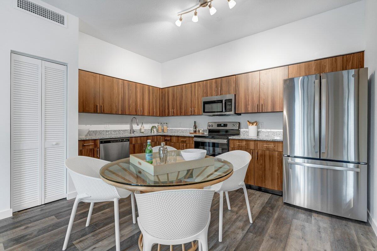 A kitchen features wood-grain cabinets, stainless steel appliances, granite countertops, and a round dining table — 4290 Lakewood Road Unit 107, FL 33461, FL